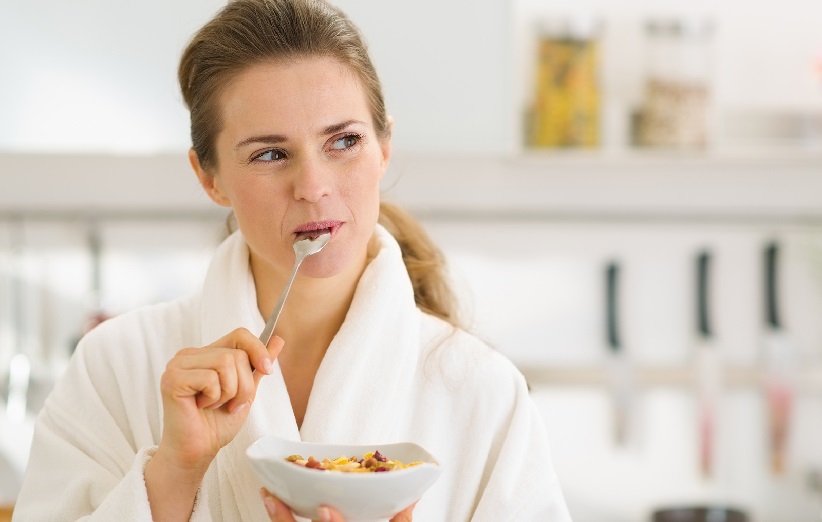 happy young woman in bathrobe eating healthy breakfast